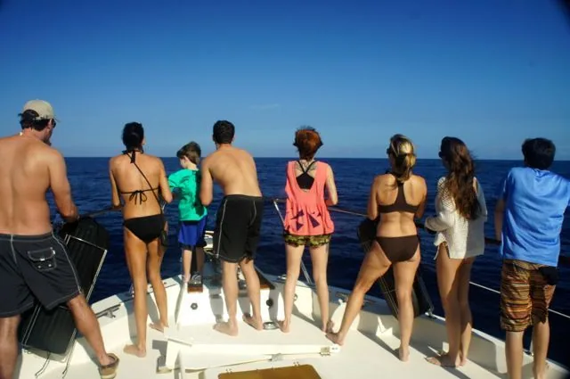 A group of people standing on a boat looking at the ocean