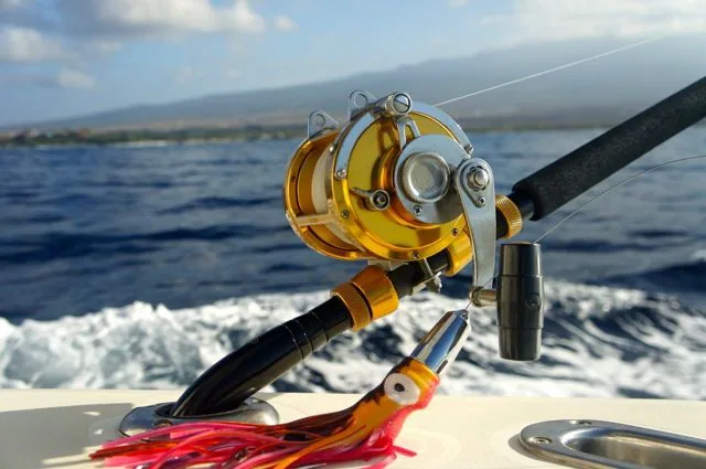 A fishing rod and reel are on a boat in the ocean.
