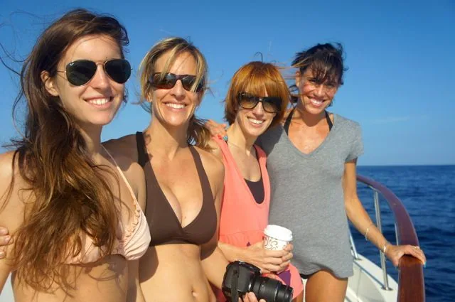 Four women are posing for a picture on a boat in the ocean