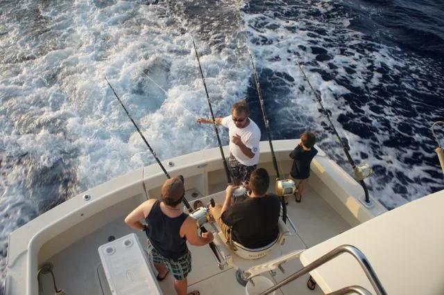 A group of people are fishing on a boat in the ocean.
