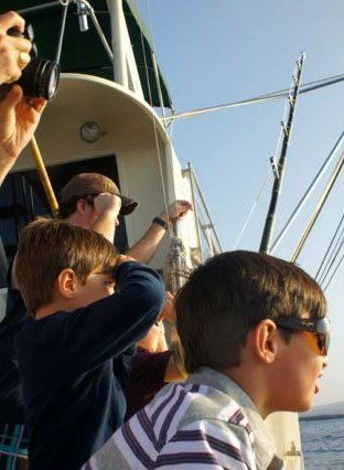 A group of people on a boat looking through binoculars