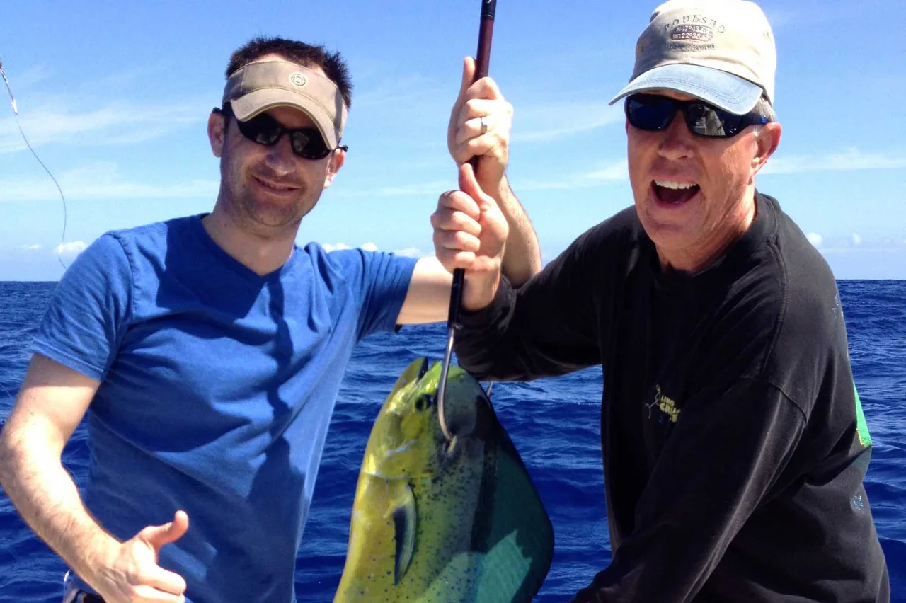 Marlin Grando: two men on a boat holding a fish and giving a thumbs up